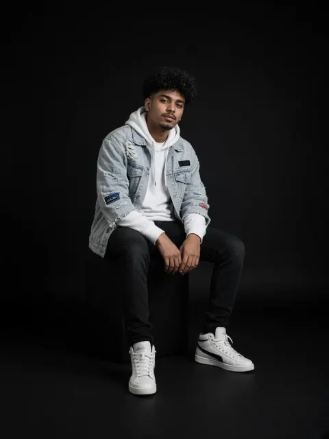 Boy Sitting in Denim Jacket on Dark Studio