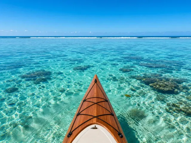 First-Person Perspective Kayaking Across Crystalline Lagoon Toward Distant Reef