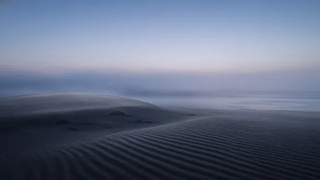 Solitary Twilight Coastal Sand Ridge Emerging into Quiet Sea Mist