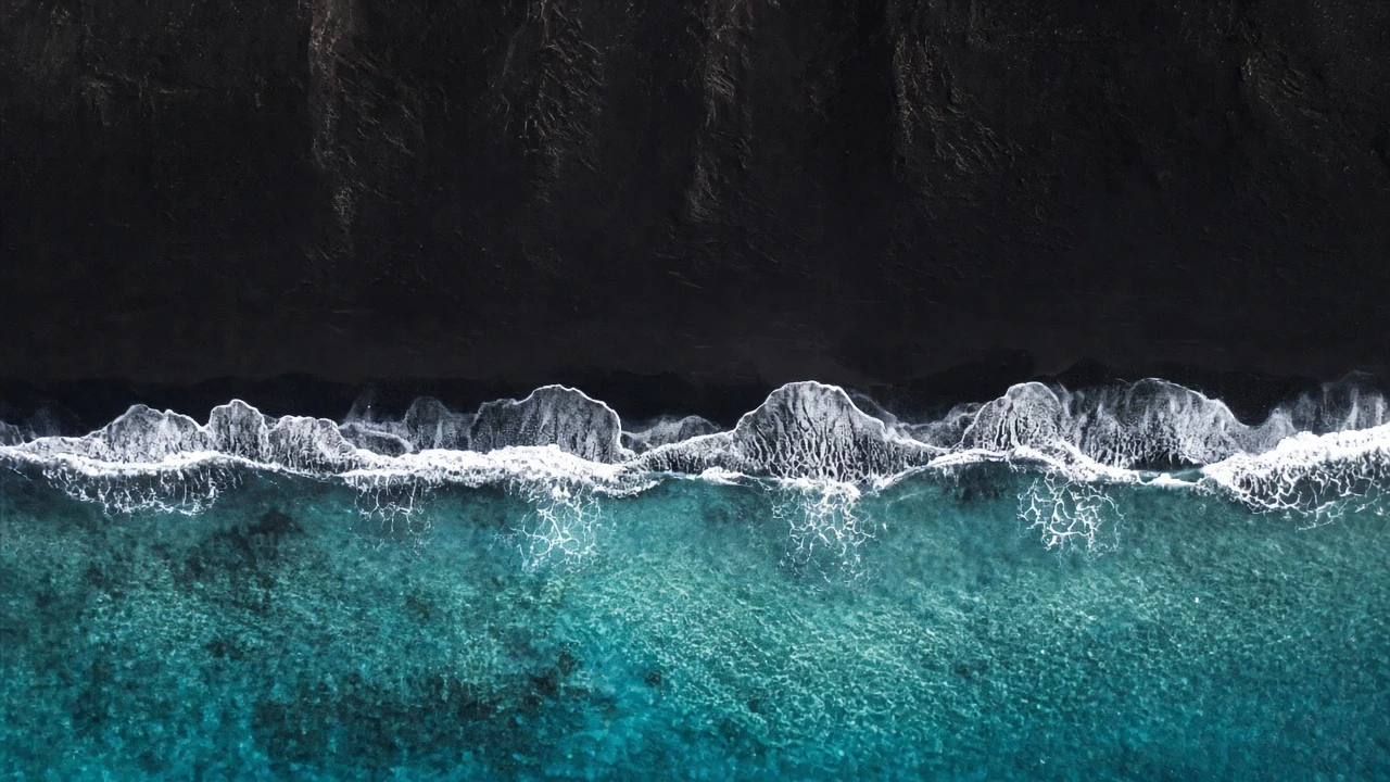 Aerial Turquoise Tide Breaking over Pristine Volcanic Black Sand
